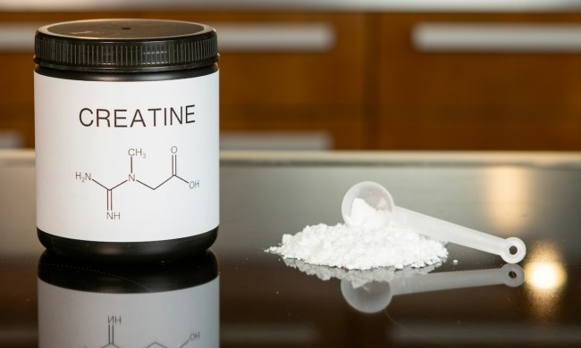 Creatine powder with some on table with a spoon