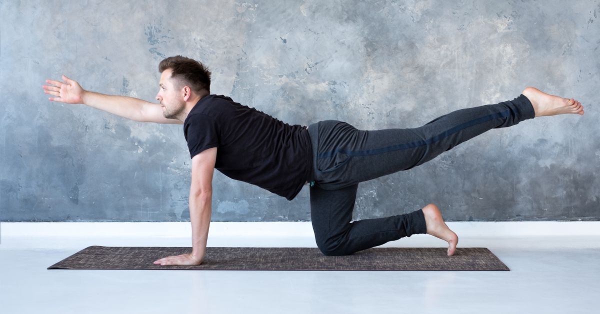 man in black doing bird dog exercise