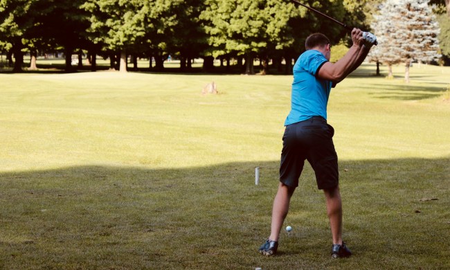 A person taking a swing on a golf course.