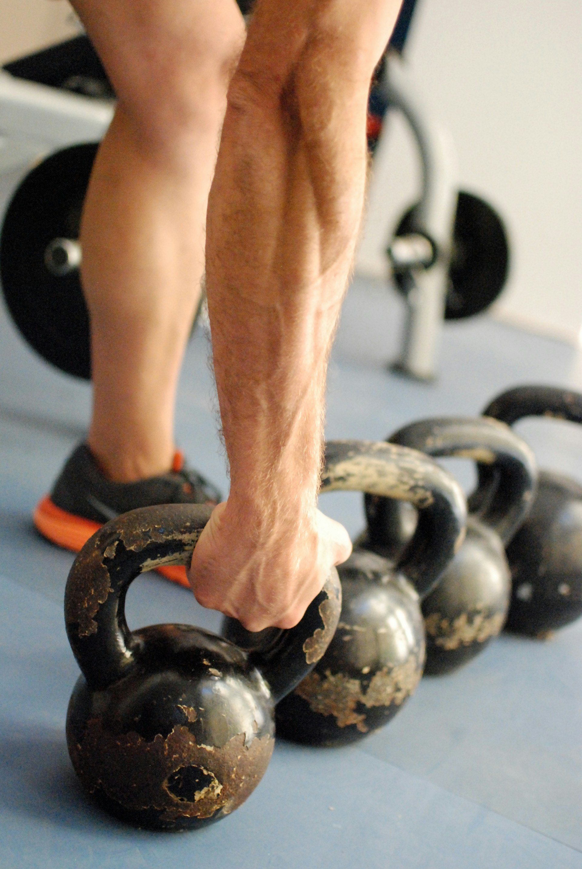 Man picking up kettlebell just hand and leg close up view in gym