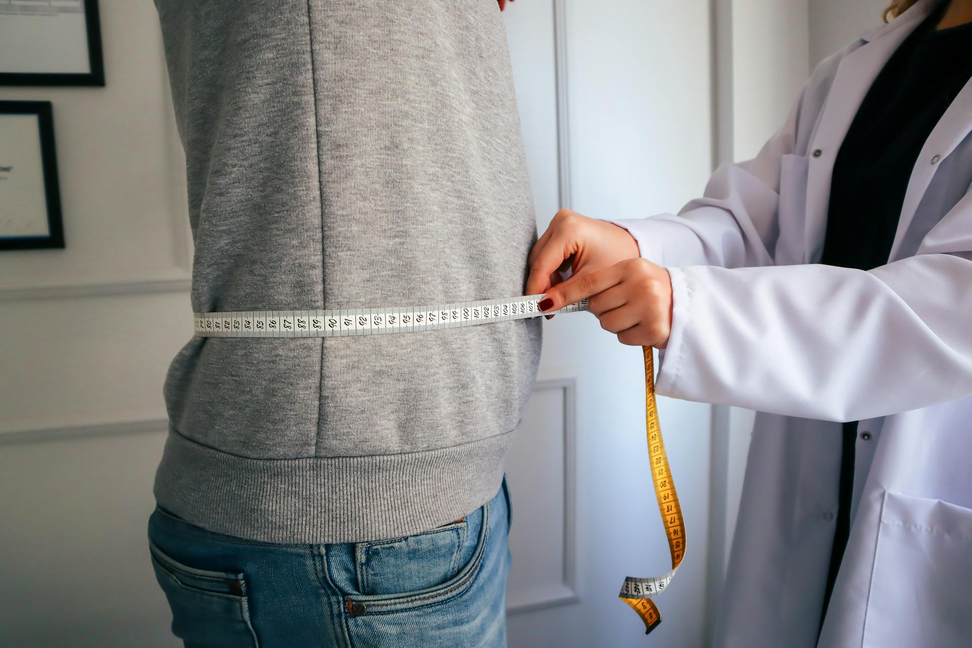 Doctor measuring a man's waist circumference