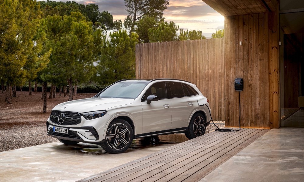 White 2025 Mercedes-Benz GLC 350e 4MATIC SUV plugged in to home charger left front three-quarter view.