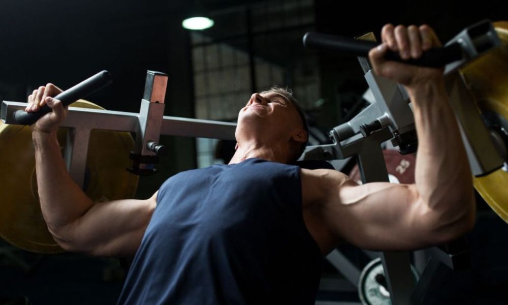 man squinting as he uses a chest press machine