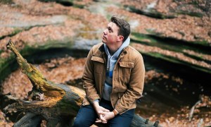 Man in brown jacket sitting in nature