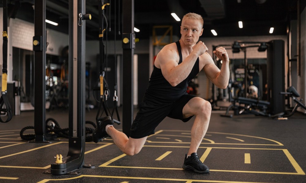 Man doing TRX bulgarian split squats.