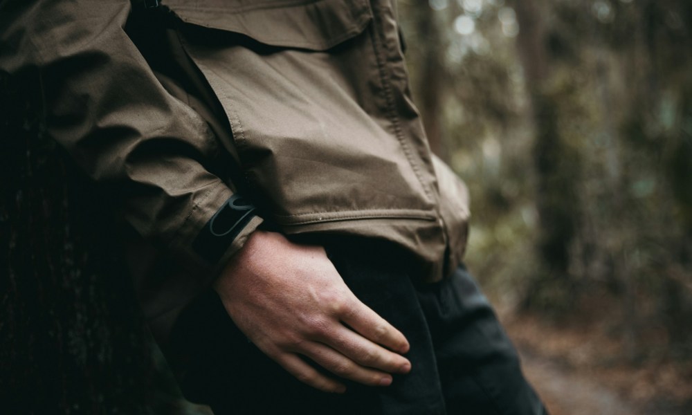 man in jacket leaning against tree