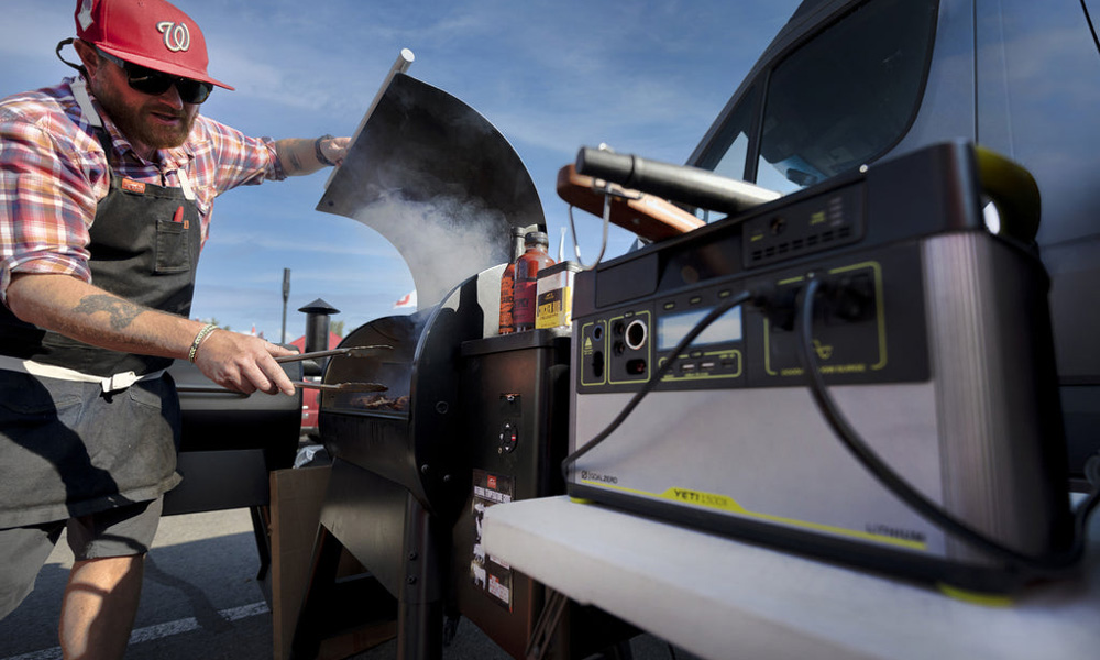 Man grilling and tailgating with a Goal Zero portable power station in the foreground.