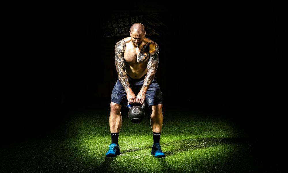 man swinging kettlebell with shorts blue shoes black background kettlebell swing pexels