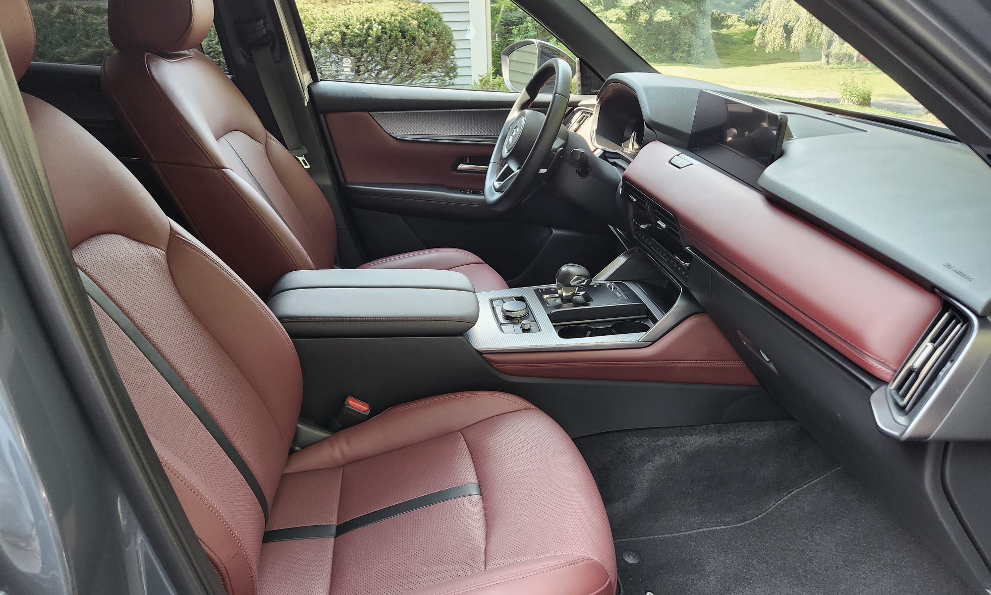 2025 Mazda CX-70 PHEV interior view of front seats, console, and dashboard taken from open passenger side door.