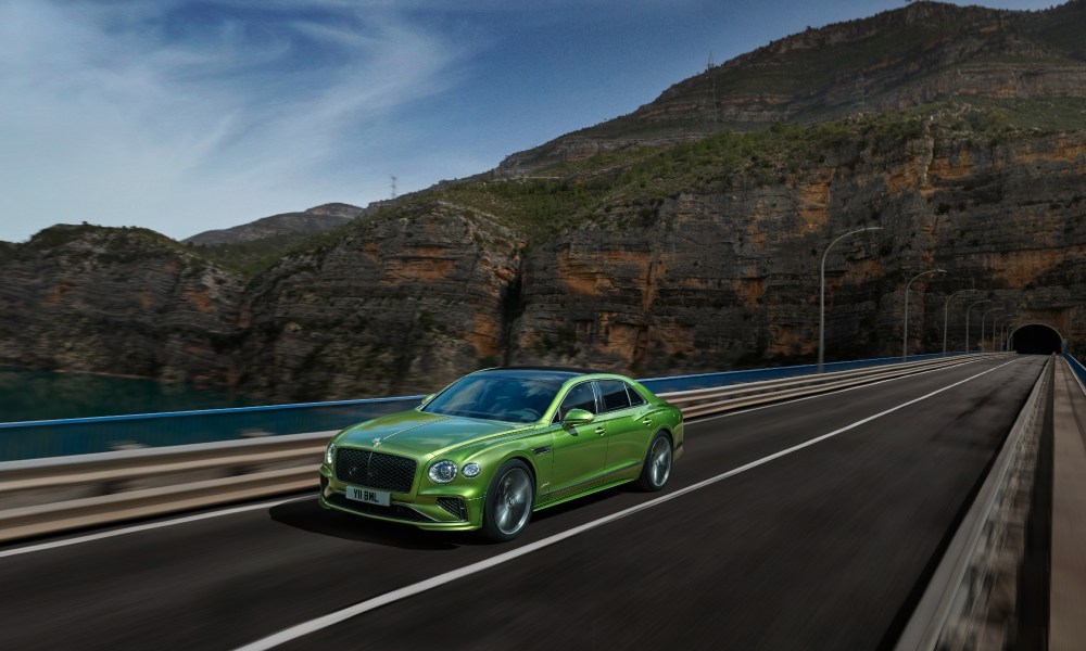 Bentley New Flying Spur driving on a highway out of a mountain tunnel left front three-quarter view.