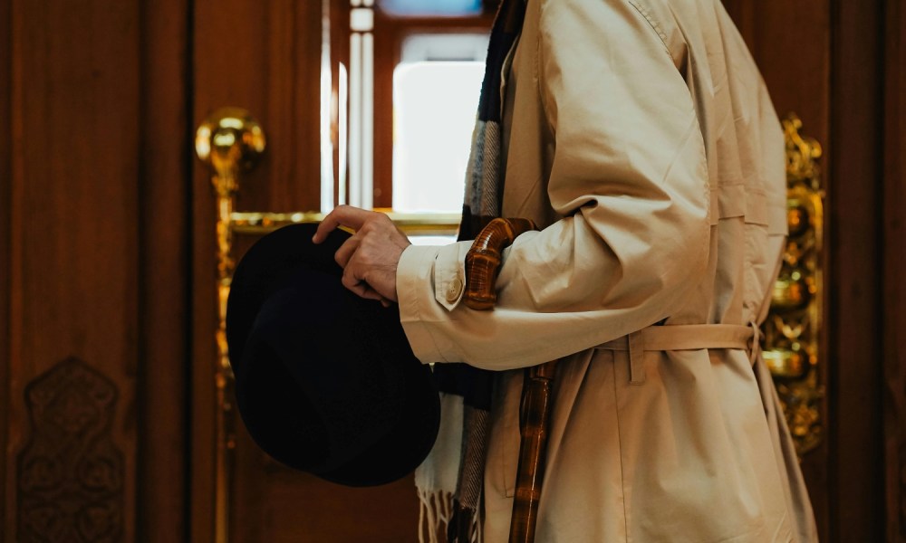 Man in trench coat with umbrella and hat