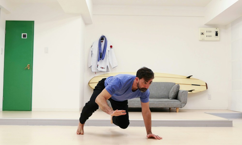 man doing bear crawl in room grey couch in background