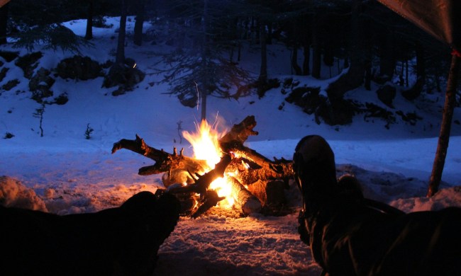 Two people sitting by a campfire at night in the winter