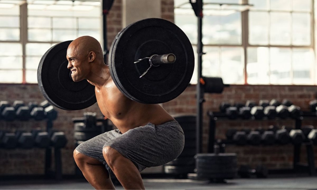 Man doing a squat with barbell wearing gray shorts