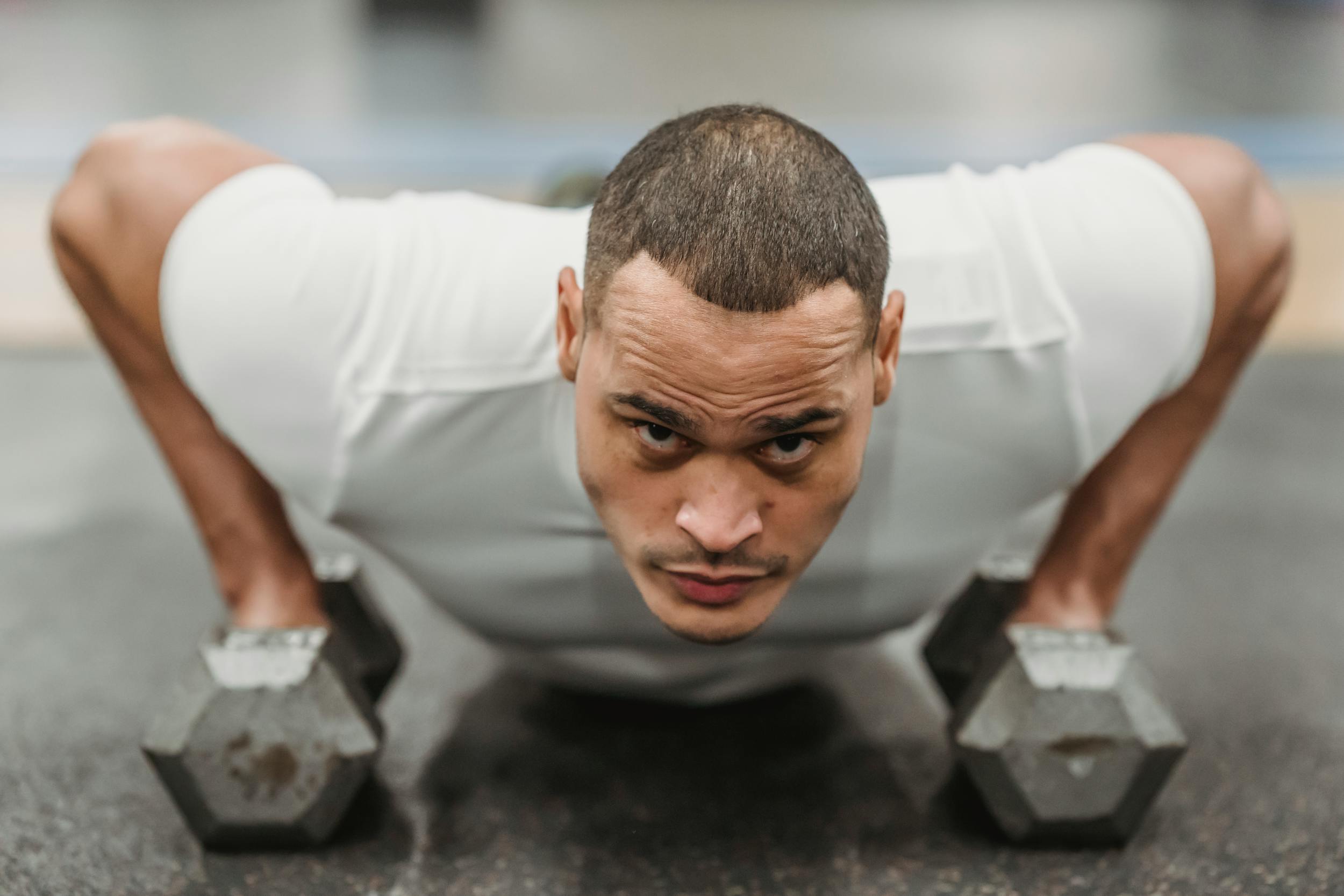 man wearing white shirt doing dumbbell renegade row