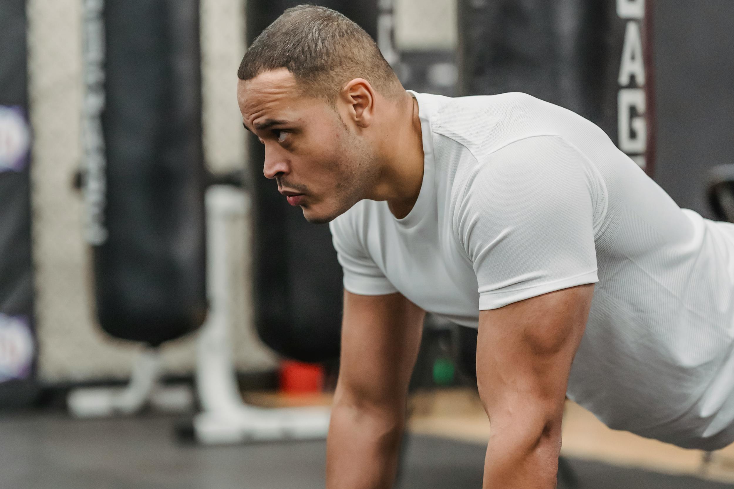 side view of man white shirt doing renegade dumbbell row