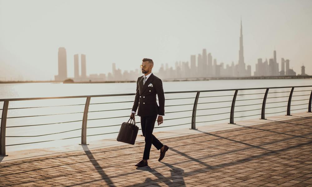 Busy business man walking by the water in a business suit with sunglasses dressed sharp