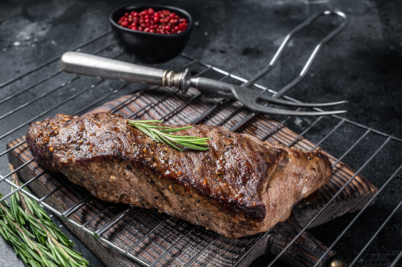 BBQ grilled tri-tip beef steak on a grill. Black background