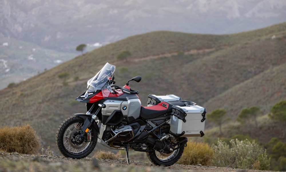 2025 BMW R 1300 GS Adventure left profile view parked on a hillside with mountains in the background.