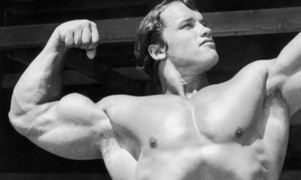 Arnold flexing shirtless black and white pic Getty