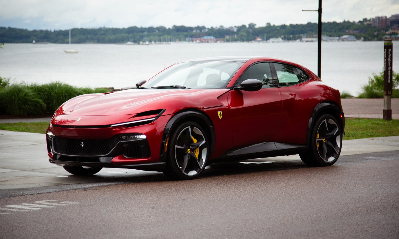 Red Ferrari Purosangue parked by water