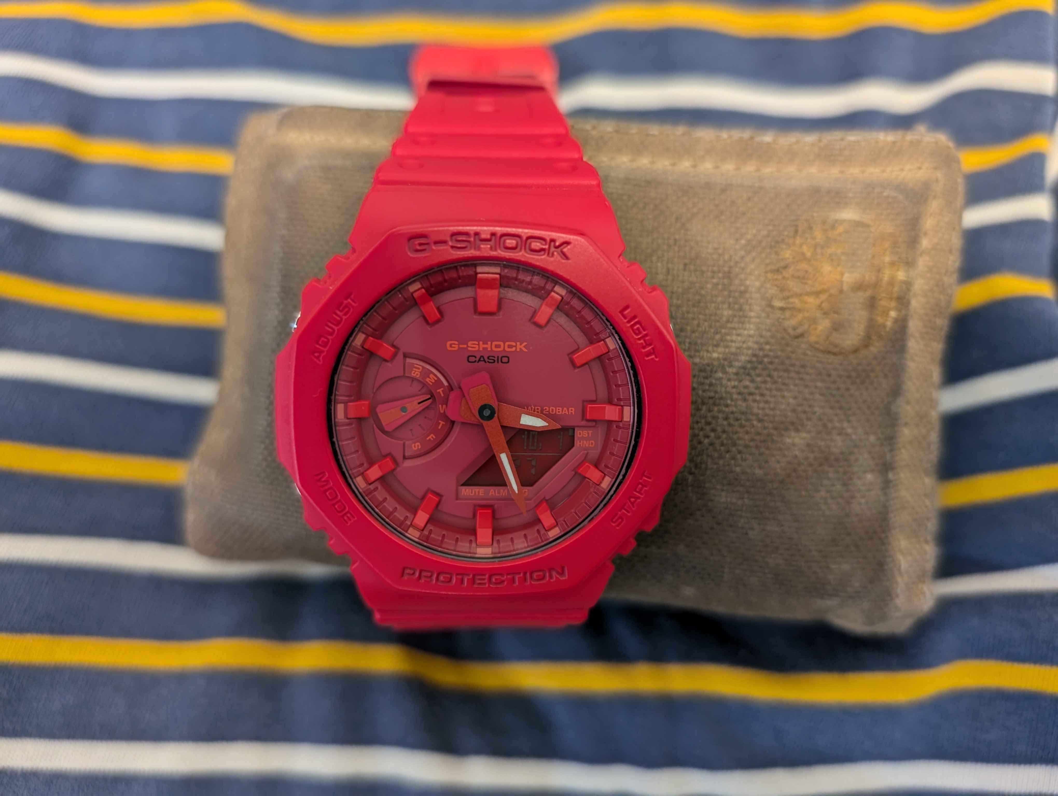 A red Casio G-Shock GA-2100 strapped to a wallet, sitting on a shirt.