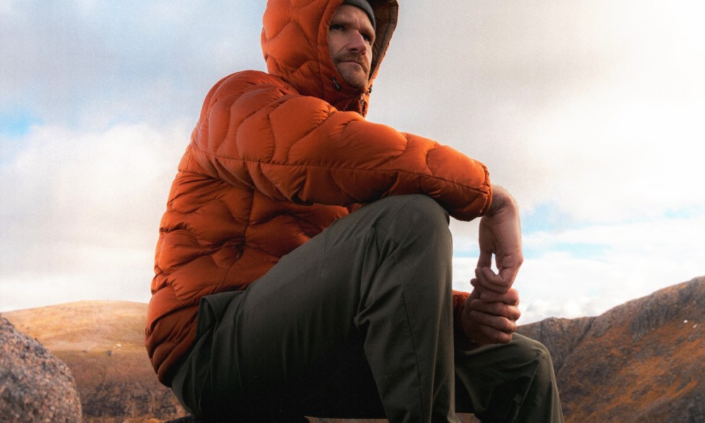 Man in Kestin jacket sitting on rock