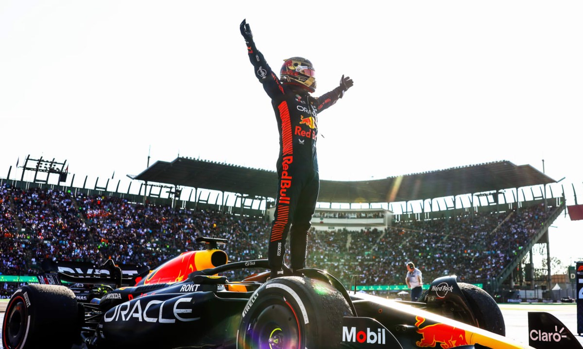 Max Verstappen standing on his race car after winning the 2023 Mexico City Grand Prix.