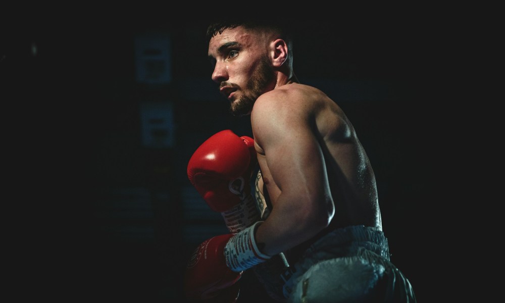 man boxing wearing red gloves shirtless dark background