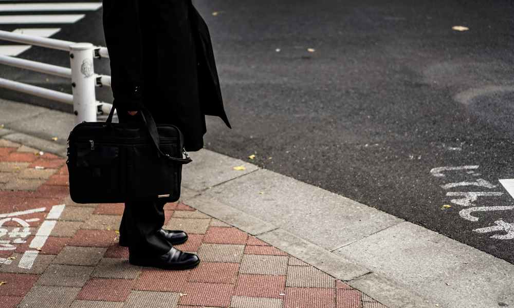 man in a suit carrying bag on street