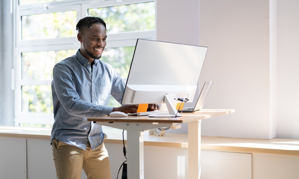 Man Using Adjustable Height Standing Desk In Office For Good Posture