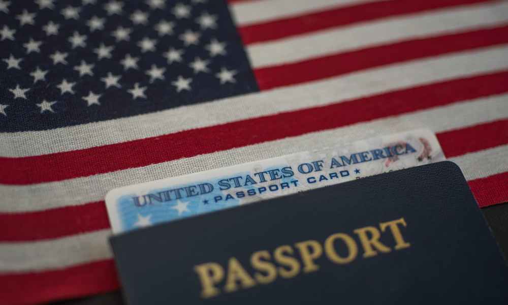 US passport card inside passport book with an American flag in the background