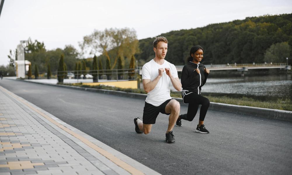 man and woman doing walking lunges outside