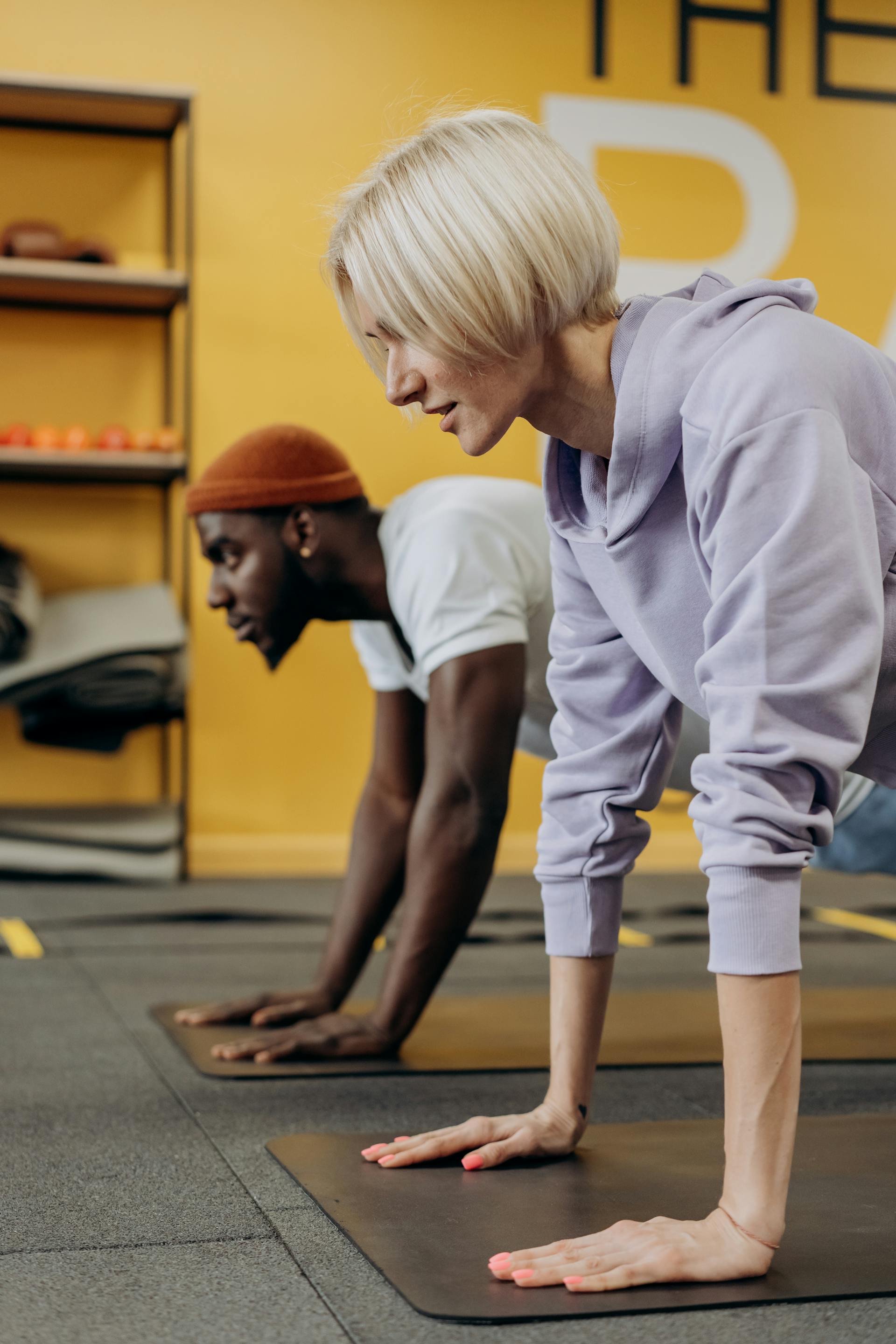 man and woman working out on floor push up yoga mat plank in gym