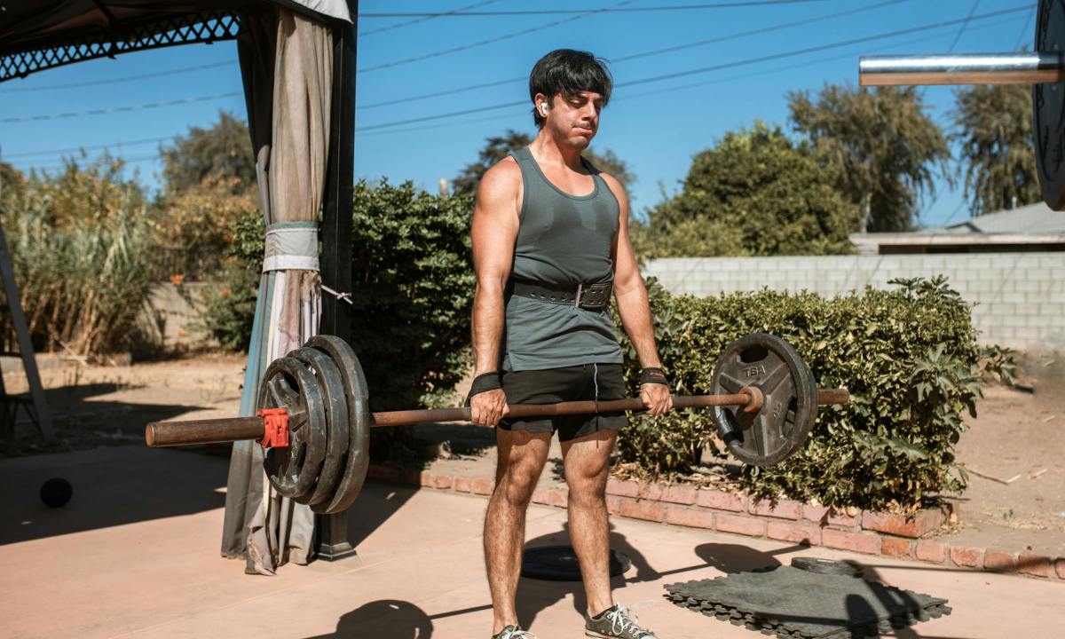 man deadlift barbell outside using lifting straps wrist strap