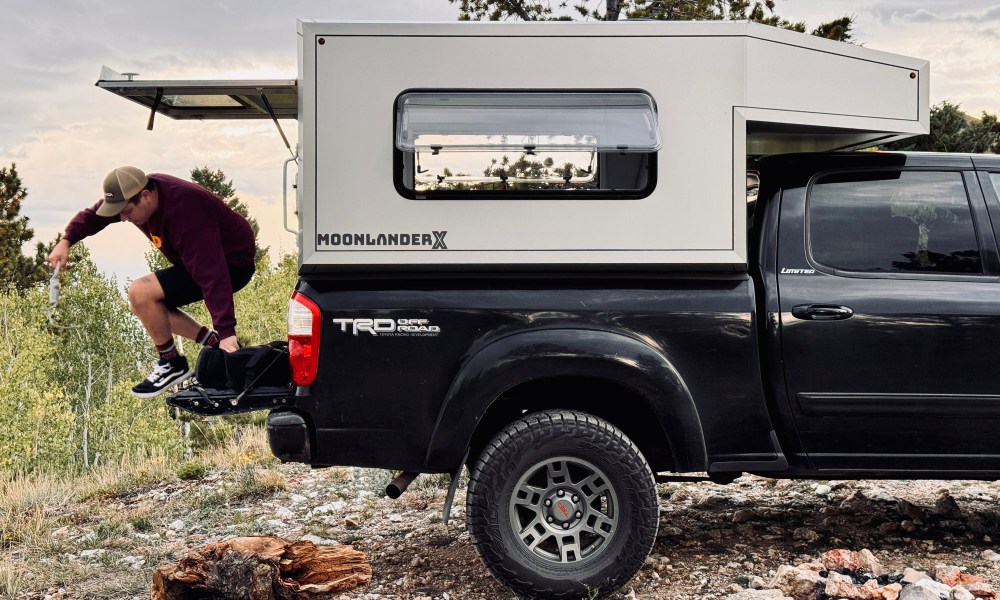 Radica Moonlander X hardshell pickup truck camper with a young man jumping out of the back.