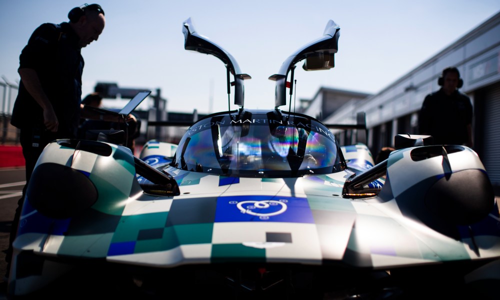 Aston Martin Valkyrie hypercar in pit lane with race engineers.