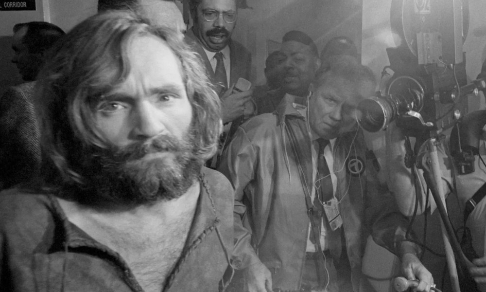 Charles Manson with a TV camera behind him