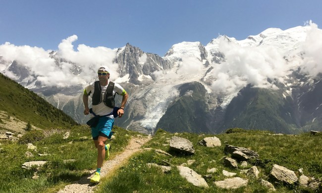 Man running on a trail with mountains in the background