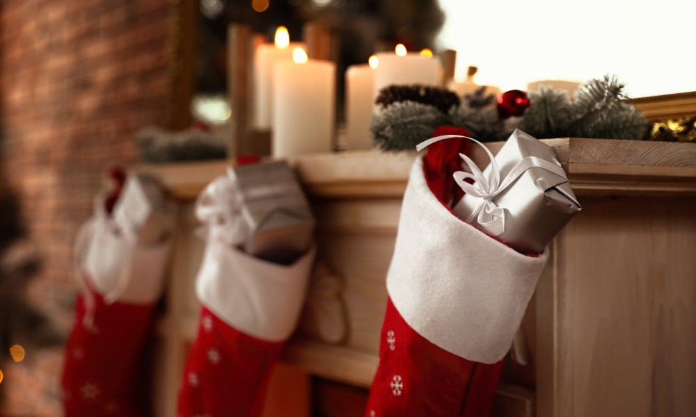 Decorative fireplace with Christmas stocking and gifts in stylish room interior