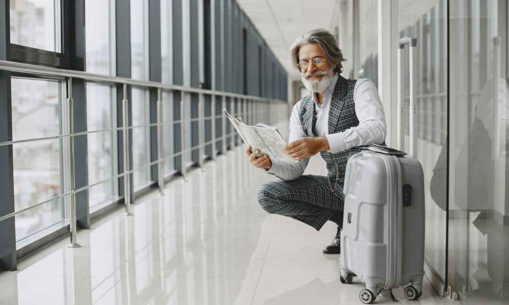 man sitting next to suitcase reading a piece of paper