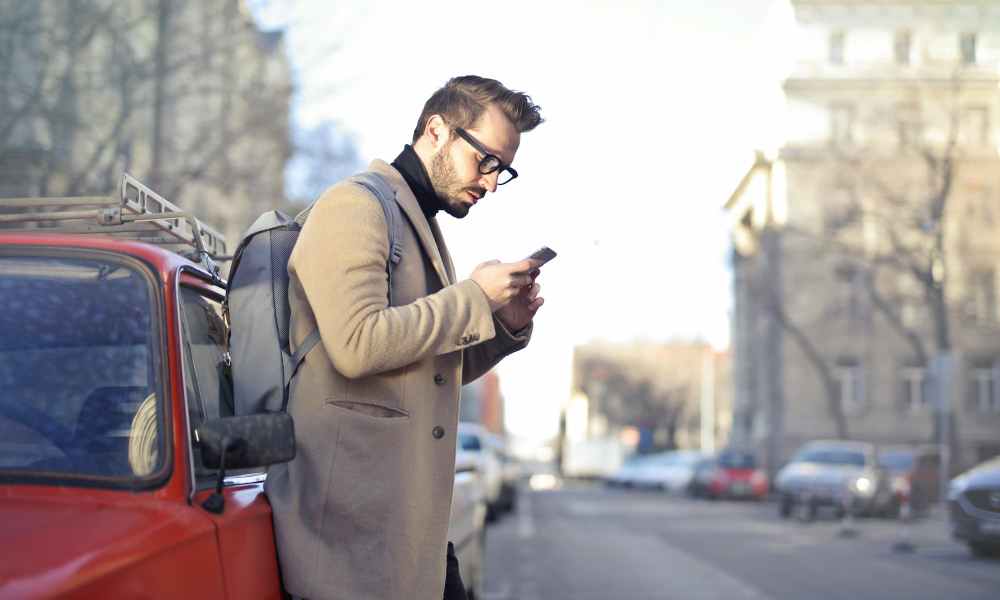 man standing outside looking at phone