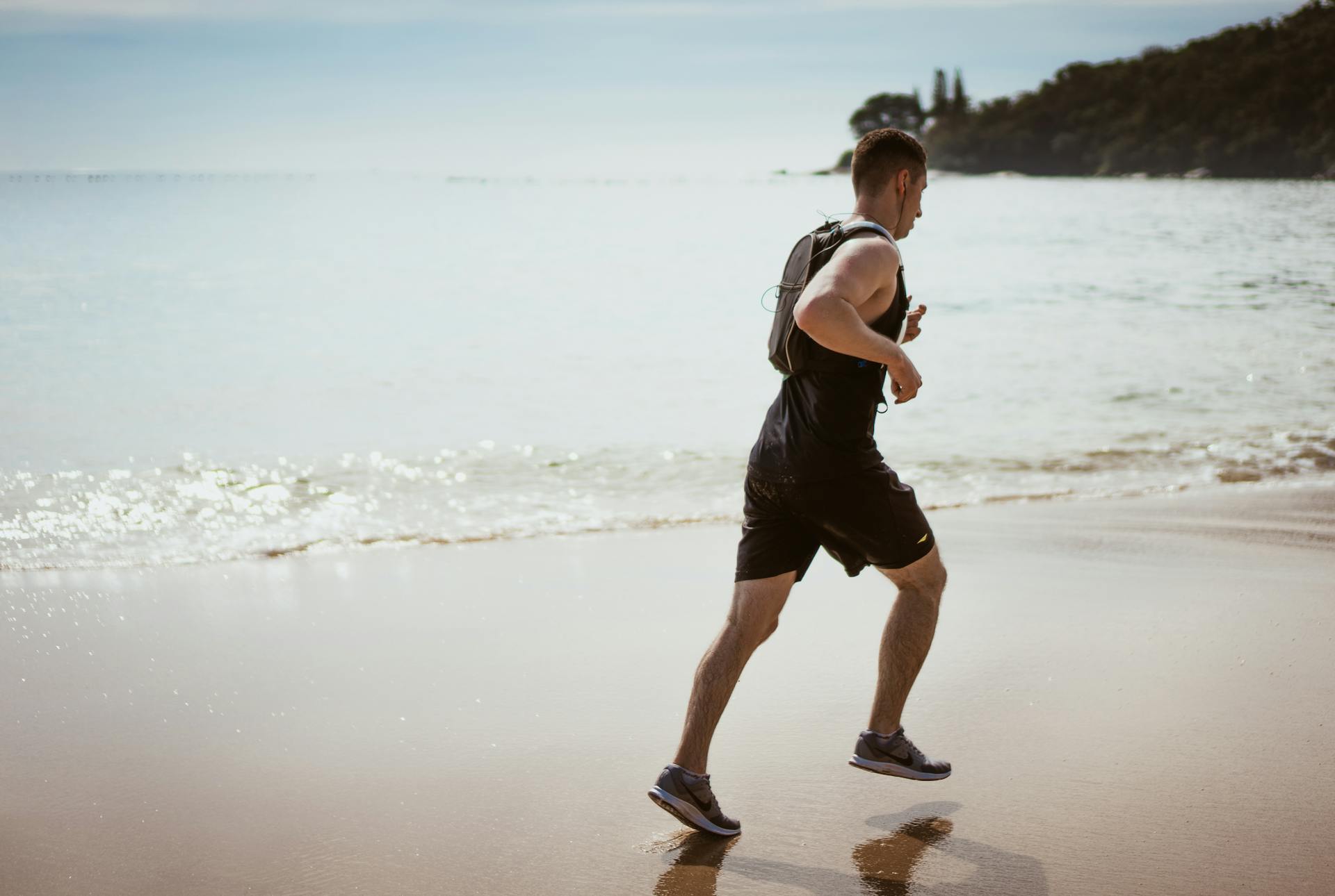 man running with headphones on beach.