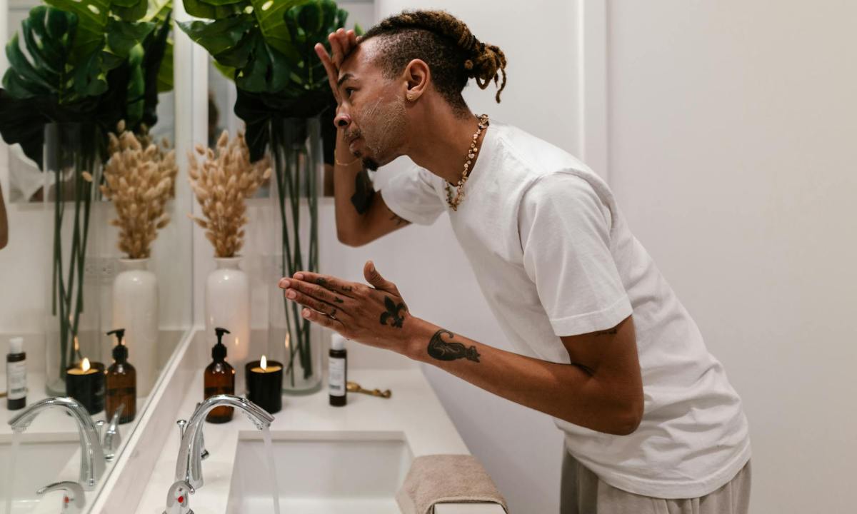 Man looking in the mirror using a skincare product