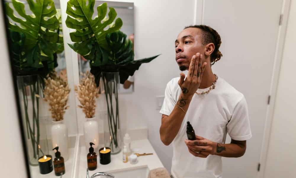 a man applying skincaare products in mirror