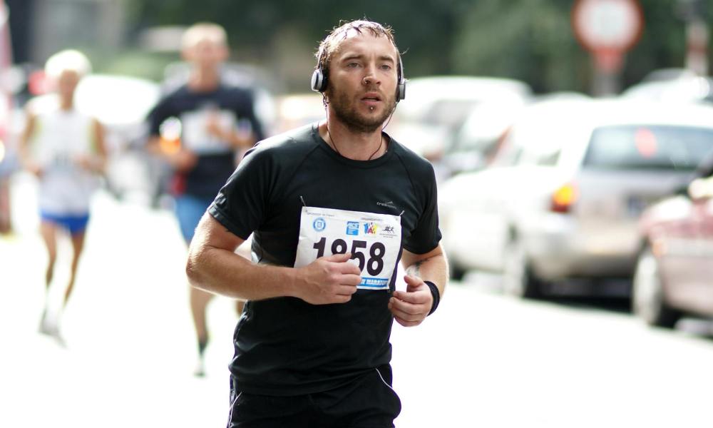 man running marathon headphones black t shirt outside