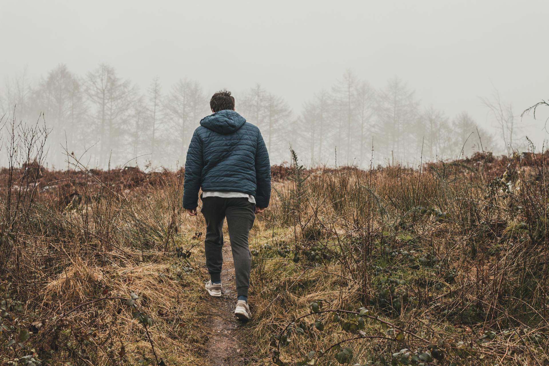 man walking outside with coat in nature