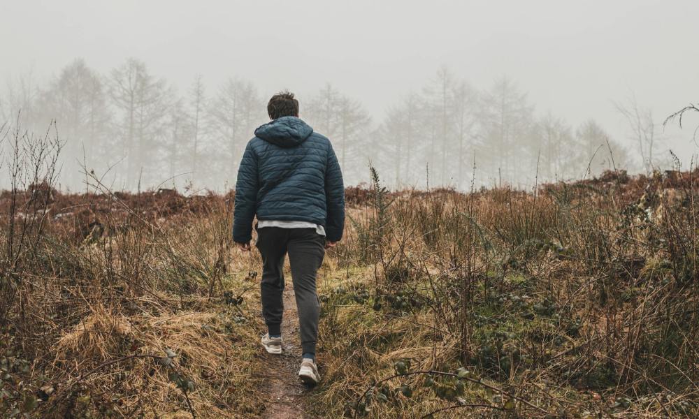 Man walking outside with coat in nature