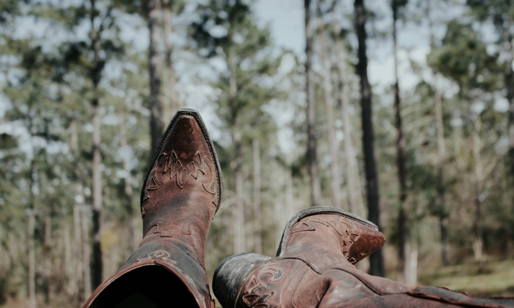 person wearing cowboy boots with nature in background