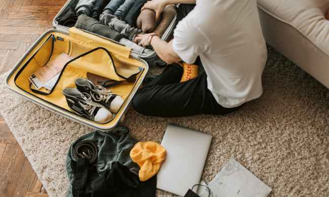 a man packing clothes in his suitcase